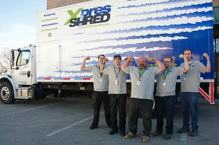 Xpresshred staff flexing in front a shredding services truck