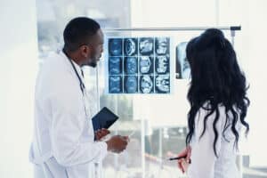 Two doctors look at an x-ray and discuss the problem. Medical technicians pointing at MRI x-ray of patient. Radiologist checking x-ray. Medical and radiology concept.